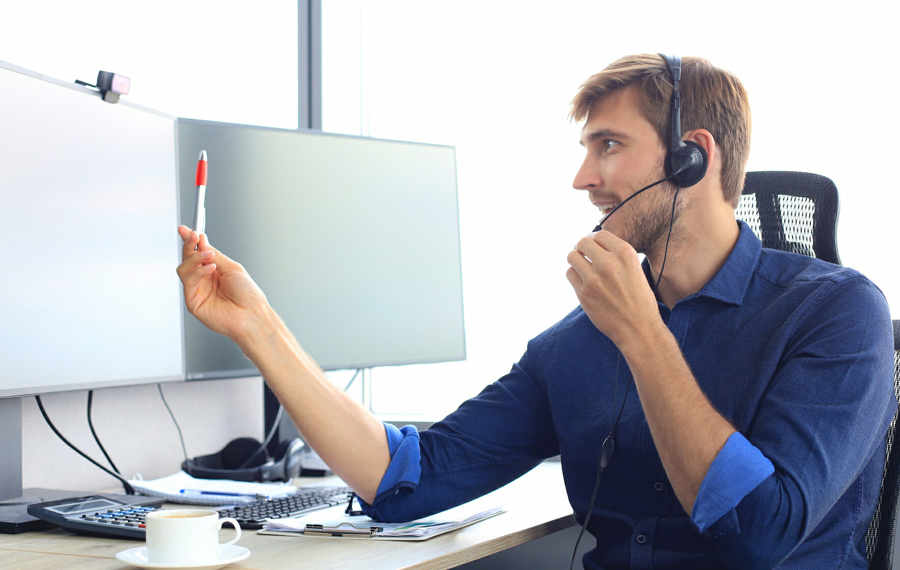 Soporte informático: Hombre joven dando soporte telefónico des de su oficina