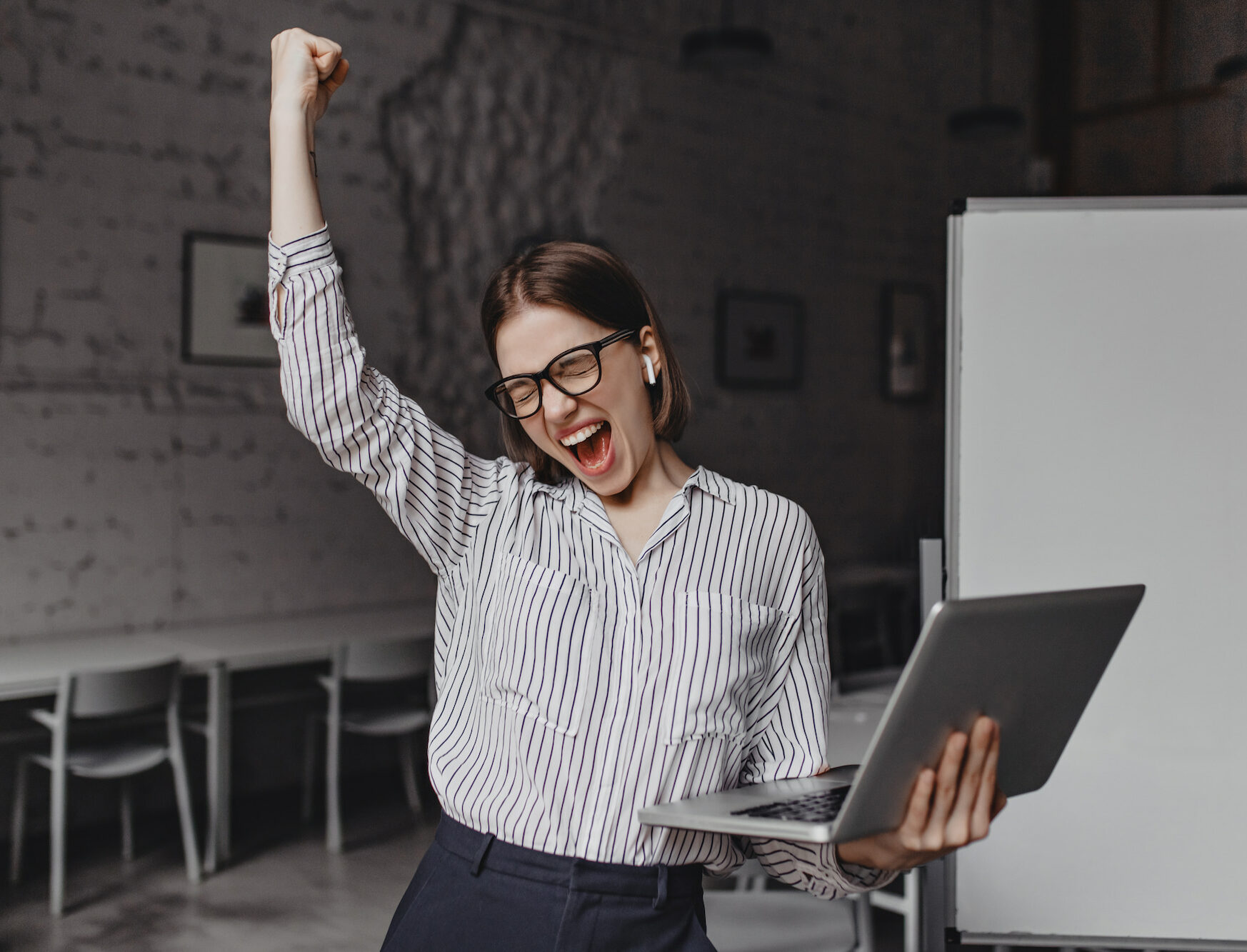 Persona celebrando con una laptop en mano, simbolizando los beneficios del desarrollo web.