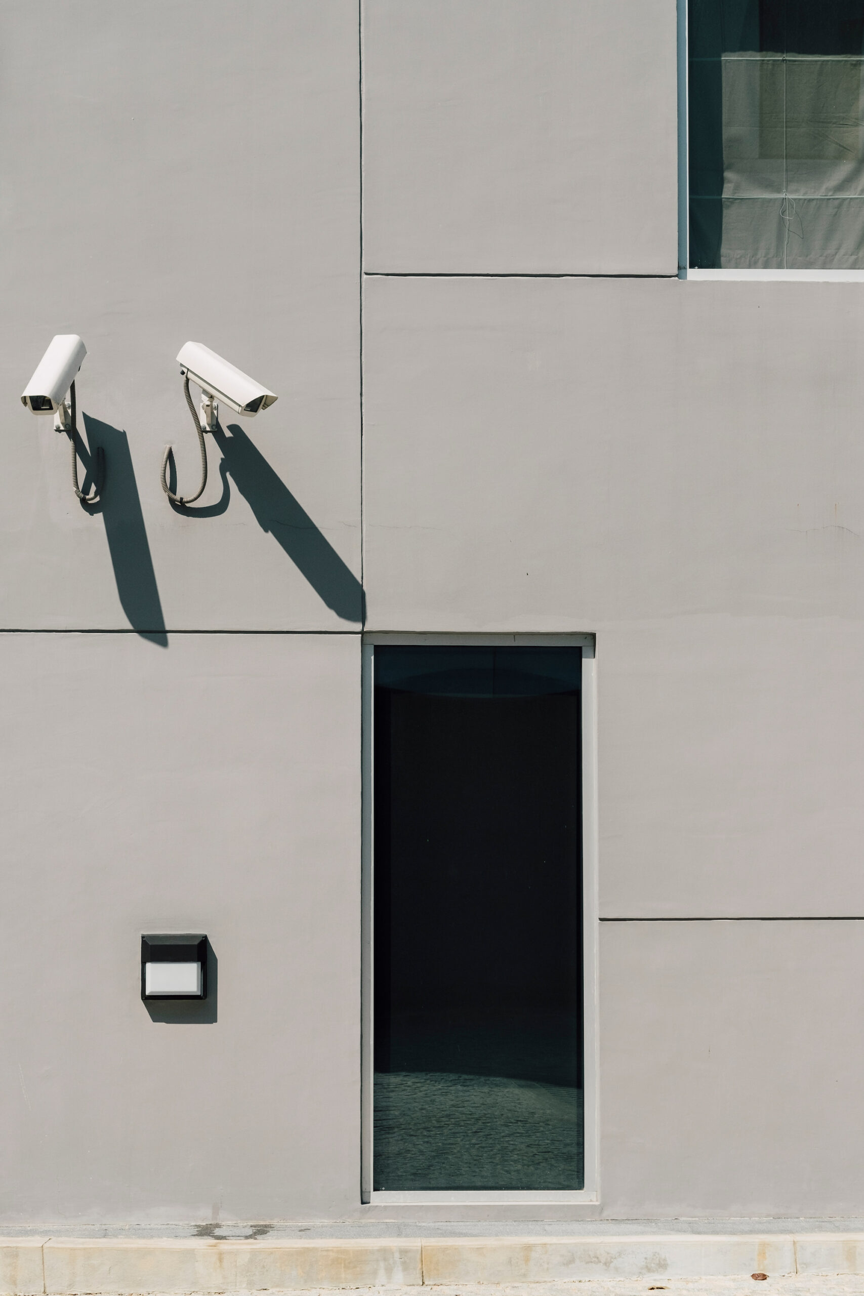 Dos cámaras de seguridad montadas en la pared exterior de un edificio, apuntando en diferentes direcciones para el control de intrusión.