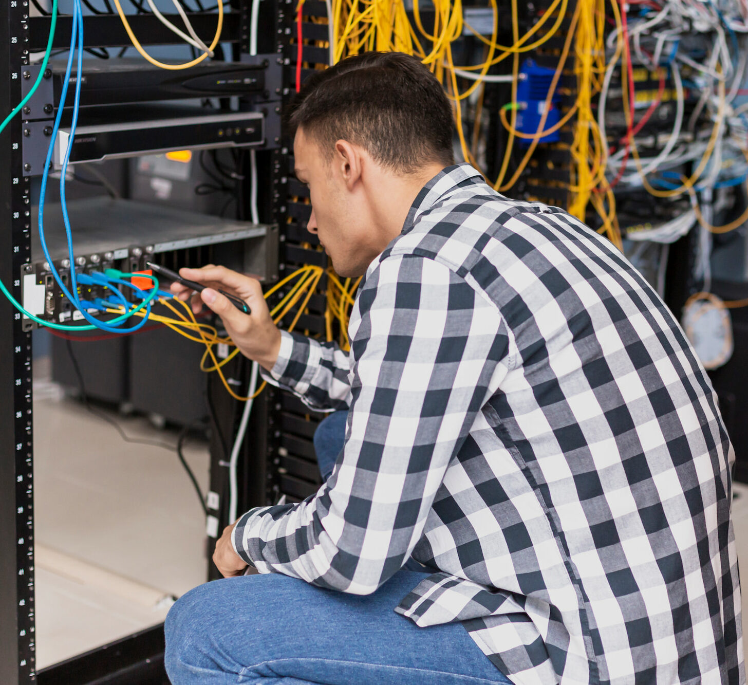 Técnico de redes configurando un rack de servidores con cableado estructurado.