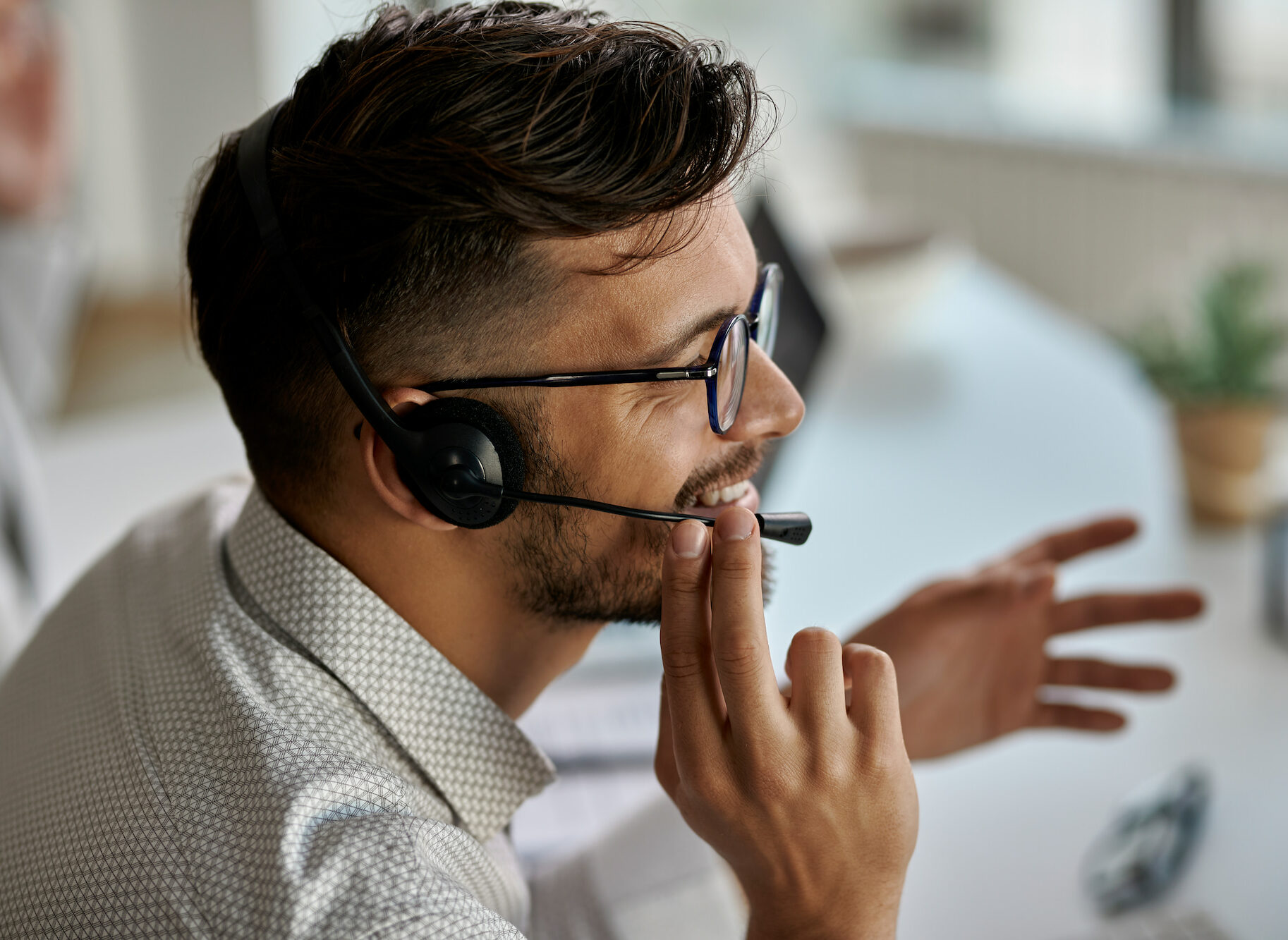 Persona con auriculares gesticulando durante una conversación en un entorno de oficina.