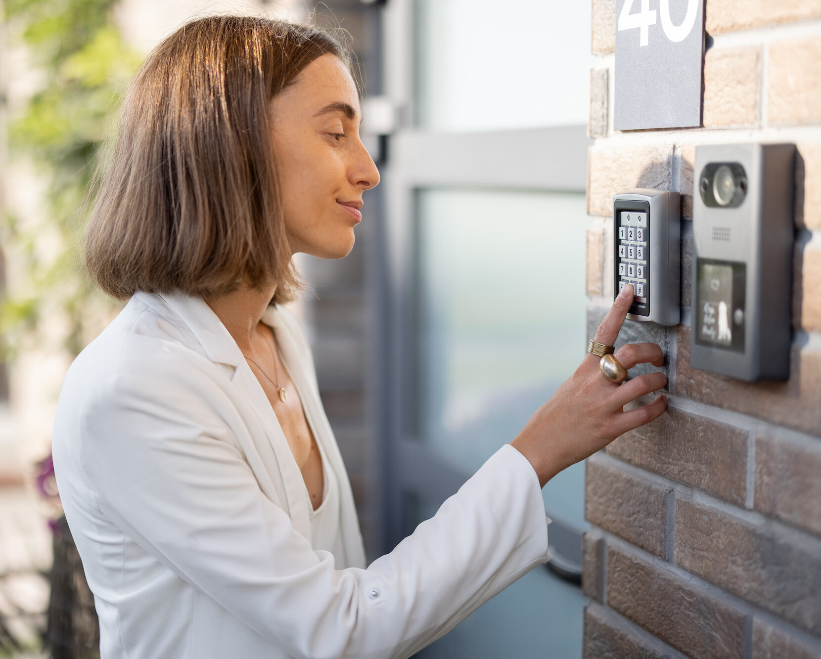 Chica ingresando un código en un sistema de intercomunicación y control de acceso.