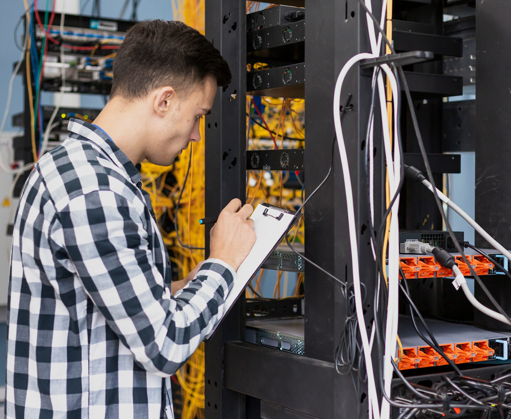 Imagen de un individuo sosteniendo un portapapeles y revisando la instalación de fibra óptica.